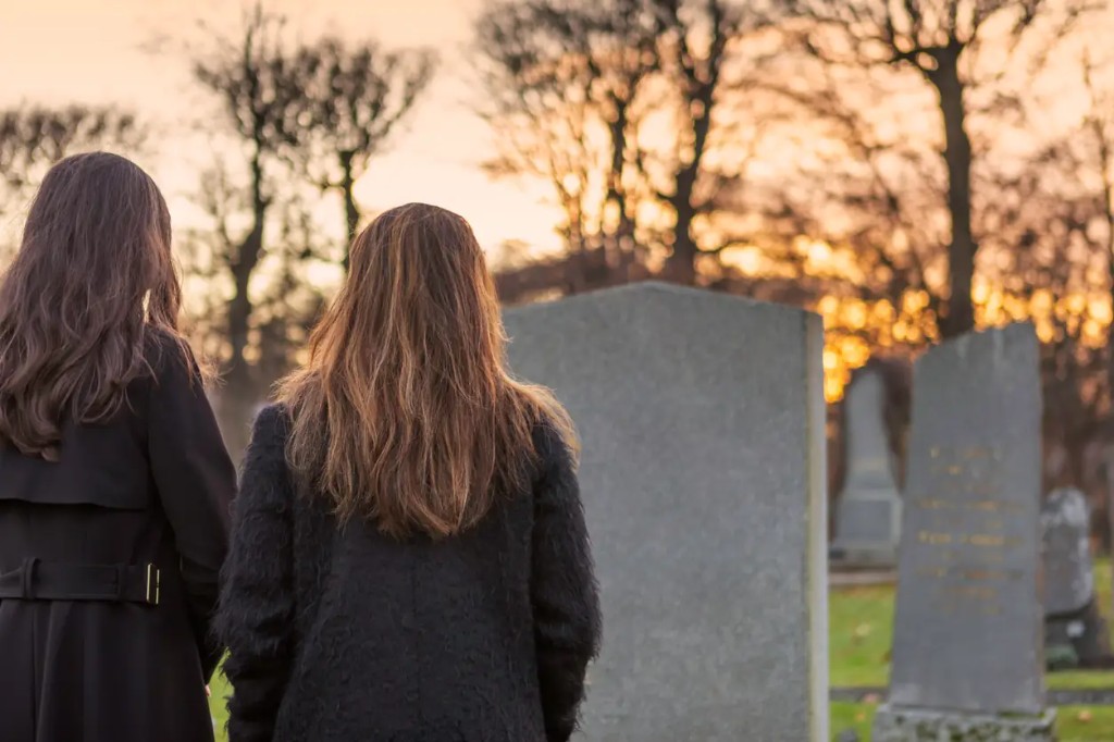 Deux personnes se recueillant devant un monument funéraire